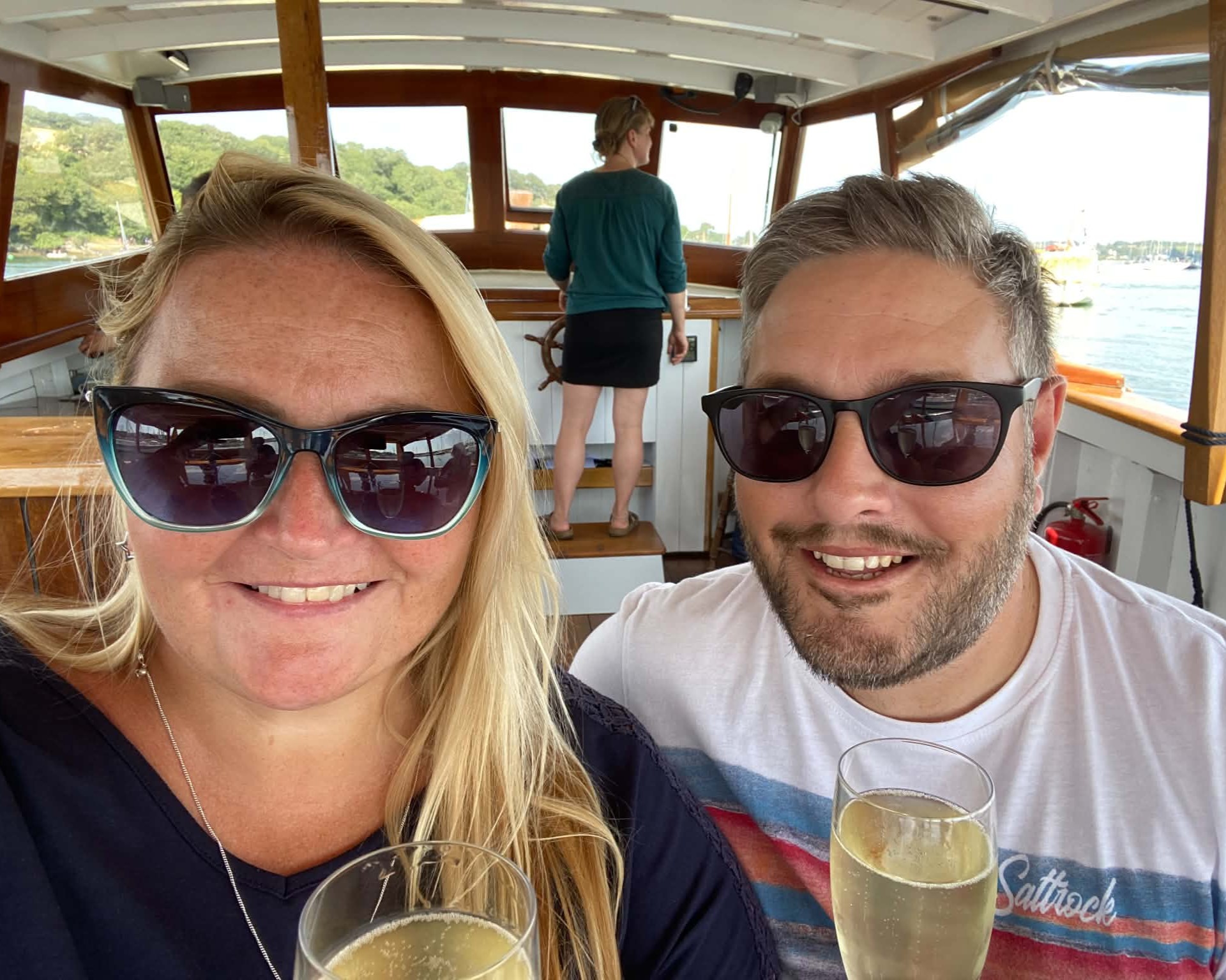 Neil and Carolanne raising a glass together on a boat